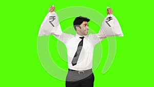 Happy businessman holding money bags on green background