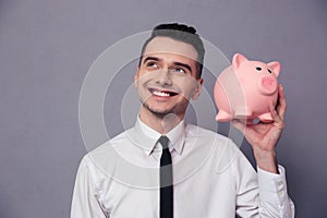 Happy businessman holding pig money box