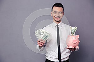 Happy businessman holding pig money box