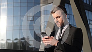 Happy businessman holding a smartphone and laughing. Joyful man-winner with a gadget in his hands.