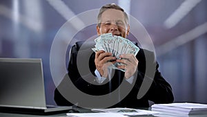 Happy businessman hugging bunch of dollars, successful start up, contract