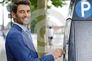 happy businessman inserting ticket into parking machine