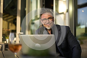 Happy businessman with laptop in hotel