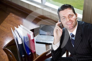 Happy businessman on mobile phone in office