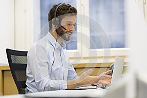 Happy Businessman in the office on the phone, headset, Skype