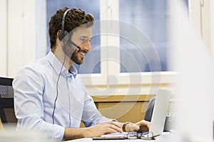 Happy Businessman in the office on the phone, headset, Skype photo
