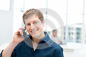 Happy businessman phoning in his office