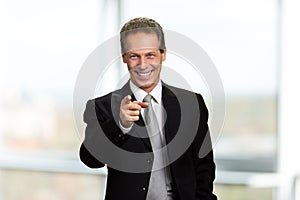 Happy businessman pointing with finger forward.