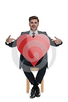 Happy businessman pointing fingers to big red heart