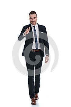 Happy businessman pointing forward and smiling while stepping