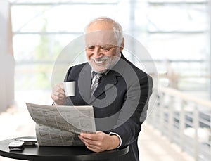 Happy businessman reading newspaper