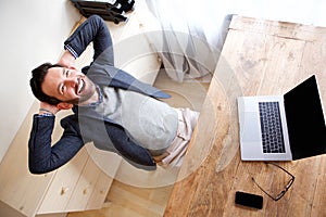 Happy businessman relaxing in office with laptop