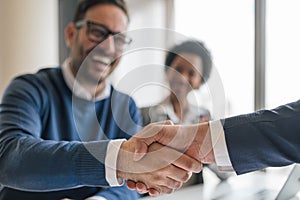 Happy businessman shaking hands with partner on successful deal at office