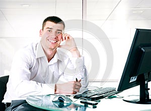 Happy businessman sits at the computer