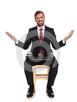 Happy businessman sitting on chair and making welcoming gesture