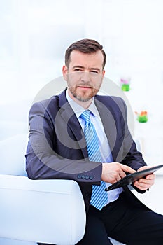 Happy businessman sitting on the sofa looking at camera in the office