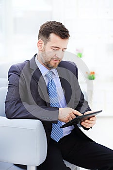 Happy businessman sitting on the sofa looking at camera in the office