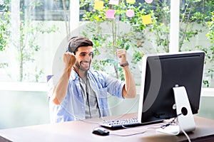 Happy businessman smilling and sitting at desk working from home on computer