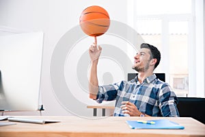 Happy businessman spining ball in office