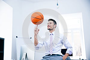 Happy businessman spining ball in office