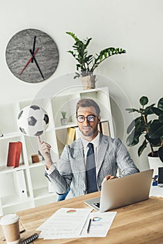 happy businessman spinning soccer ball on finger