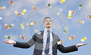 Happy businessman standing in the rain of money