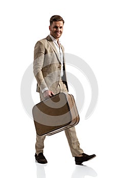 Happy businessman in suit holding luggage and smiling