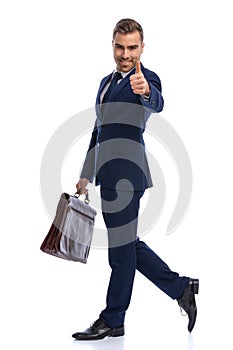 happy businessman in suit making thumbs up sign and smiling