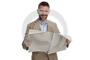 Happy businessman in suit smiling and reading newspaper