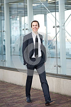 Happy businessman in suit walking on sidewalk in the city