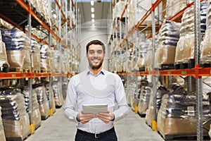 Happy businessman with tablet pc at warehouse