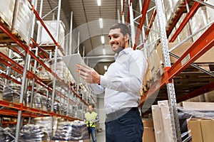 Happy businessman with tablet pc at warehouse