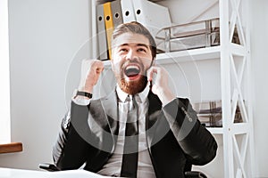 Happy businessman talking by phone and make winner gesture.