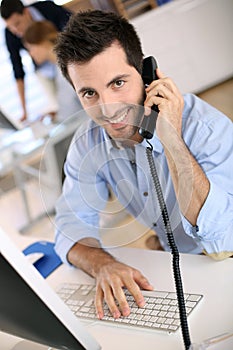 Happy businessman talking on phone in office