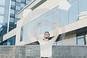 Happy businessman throwing documents in air