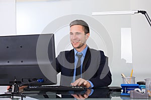 Happy businessman using computer in his office