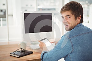 Happy businessman using digital tablet while sitting at desk