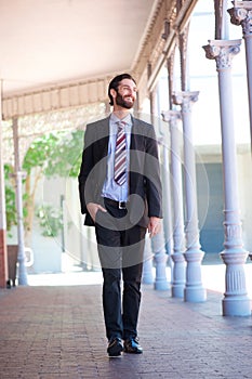 Happy businessman walking outside on sidewalk in the city