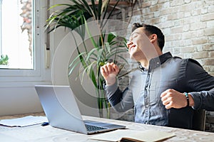 Happy businessman wearing headphones singing song at workplace, funny employee or freelancer using laptop, enjoying favorite track