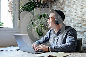 Happy businessman wearing headphones singing song at workplace, funny employee or freelancer using laptop, enjoying favorite track