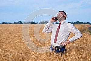 happy businessman in wheat field emotionally talking on the phone