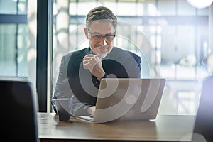 Happy businessman working with laptop in office