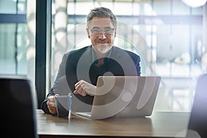 Happy businessman working with laptop in office