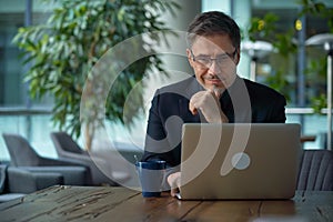 Happy businessman working with laptop in office