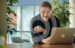 Happy businessman working with laptop in office