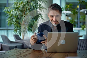 Happy businessman working with laptop in office