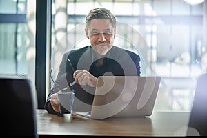 Happy businessman working with laptop in office