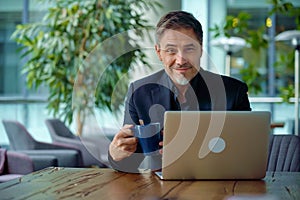 Happy businessman working with laptop in office