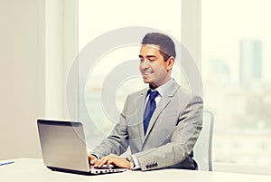 Happy businessman working with laptop in office