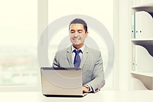 Happy businessman working with laptop in office